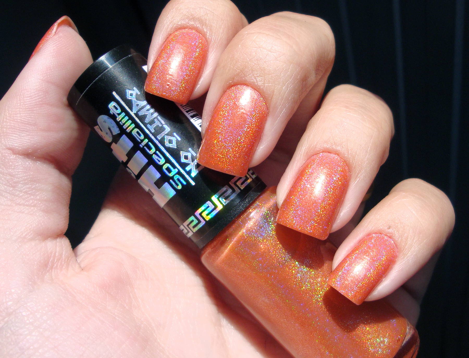 ongles oranges avec un tube de vernis orange pailleté dans la main