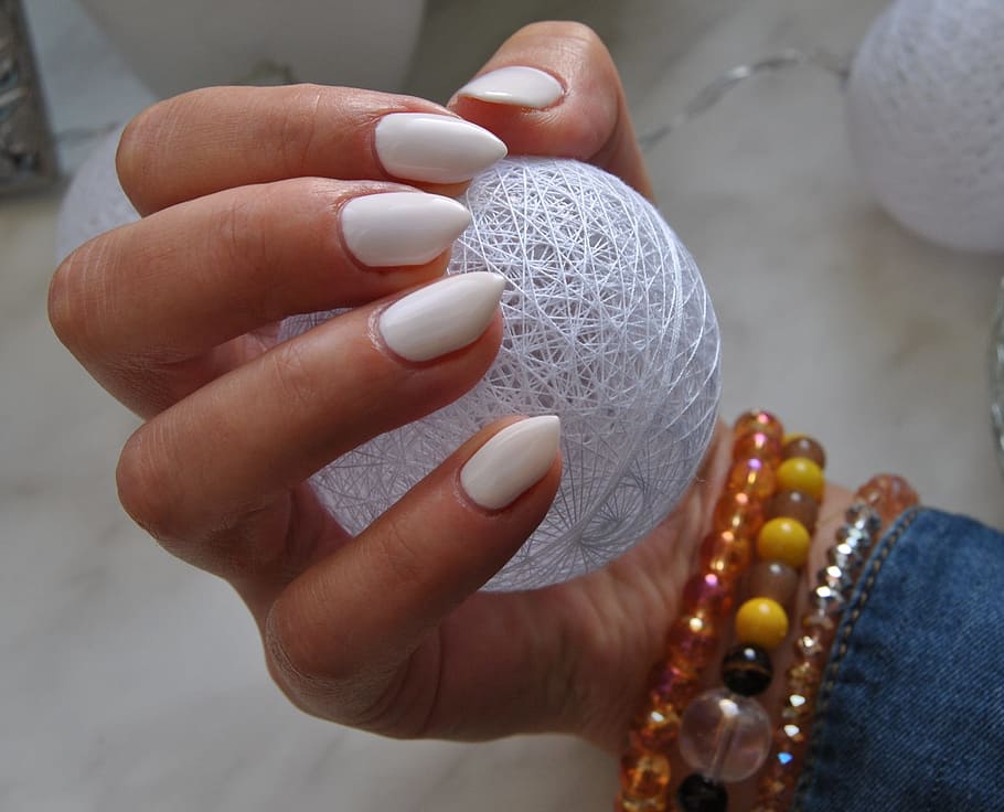 ongles blanc tenant une boule de ficelles