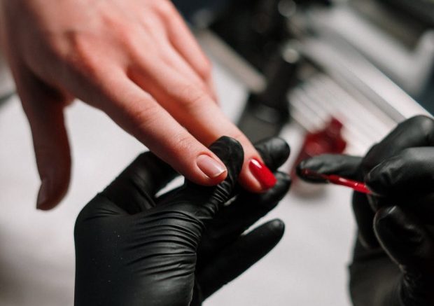 application de vernis semi-permanent rouge sur un ongle