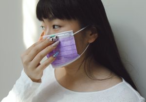 Une femme avec des ongles vernis portant un masque de protection violet