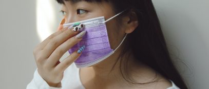 Une femme avec des ongles vernis portant un masque de protection violet